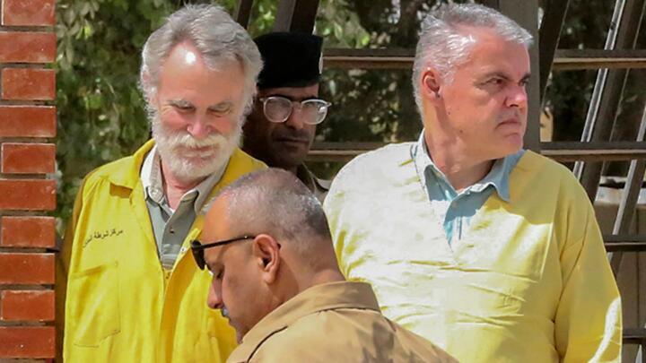 James Fitton, 66, a retired British geologist (L) and Volker Waldmann, 60, a Berlin psychologist, are dressed in yellow detainee uniforms as they arrive at a courthouse in the Iraqi capital Baghdad on May 22, 2022.